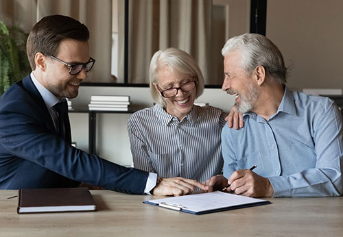 Attorney assists smiling senior couple in signing a legal document, highlighting Work With Gregory Biernacki And Biernacki